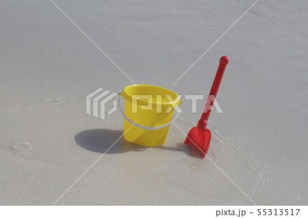 A yellow baby bucket and a red shovel stand A yellow baby bucket and a red shovel stand 55313517