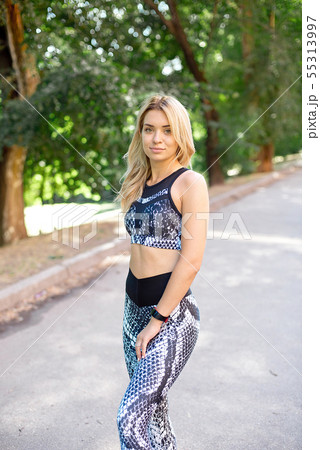 Young slim woman with a sporty body, long blond hair, dressed in a sports top and leggings, prepares 55313997