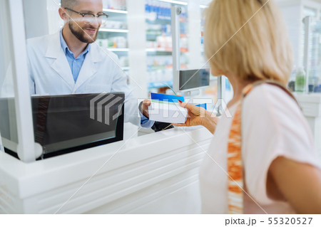 Handsome young pharmacist selling medicine for client Handsome young pharmacist selling medicine for client 55320527