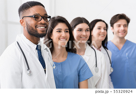 Team of doctors and interns standing in hospital in row Team of doctors and interns standing in hospital in row 55320924