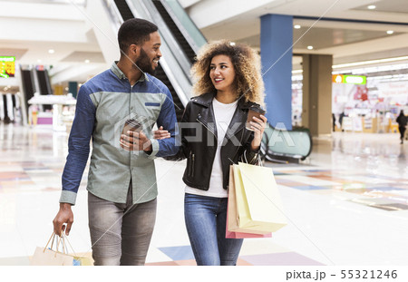Cheerful african couple with coffee to go and paper bags 55321246