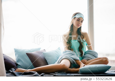 Beautiful young woman seating at window pillows in Beautiful young woman seating at window pillows in 55321626