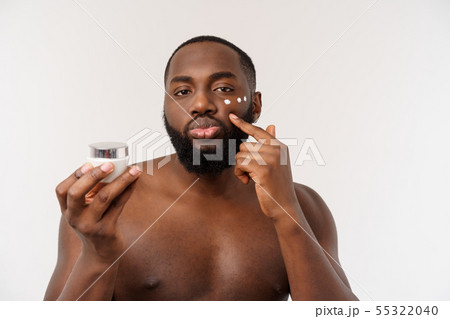 Smiling afro man applying cream on his face. Man's skin care concept Smiling afro man applying cream on his face. Man's skin care concept 55322040