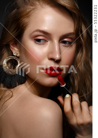 Beautiful girl with red lips and classic makeup and curls with lipstick in hand. Beauty face. Beautiful girl with red lips and classic makeup and curls with lipstick in hand. Beauty face. 55322231