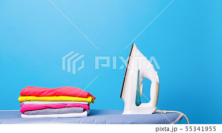Electric iron and pile of clothes on ironing board Electric iron and pile of clothes on ironing board 55341955