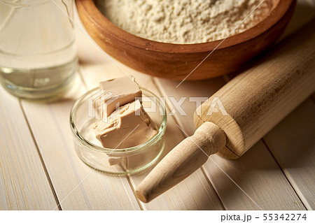 Top view of bowl of flour with yeast and rolling pin on white kitchen table Top view of bowl of flour with yeast and rolling pin on white kitchen table 55342274