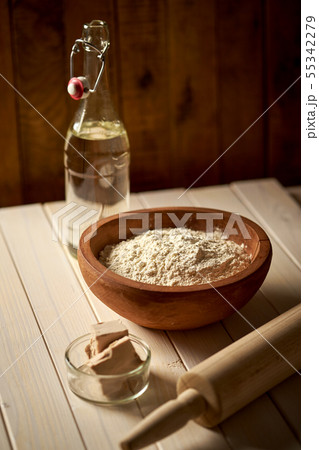 Top view of bowl of flour with yeast and rolling pin on white kitchen table Top view of bowl of flour with yeast and rolling pin on white kitchen table 55342279