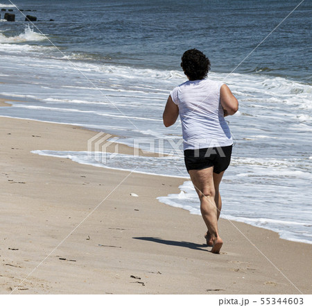 Women jogging on sand next to the Ocean 55344603