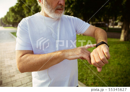 Senior man as runner with armband or fitness tracker at the city's street Senior man as runner with armband or fitness tracker at the city's street 55345627