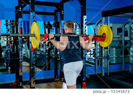 athlete performs barbell squats in the gym 55345673