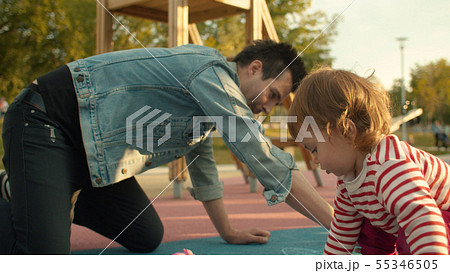 Man draws with chalks on the playground 55346505
