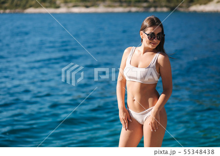 Attractive female in bikini stand in front of beautiful sea on the island. Woman on the rock. Sexy 55348438