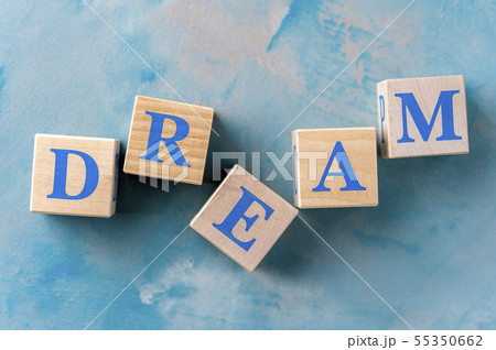 Wooden cubes with word DREAM on blue table. Wooden cubes with word DREAM on blue table. 55350662