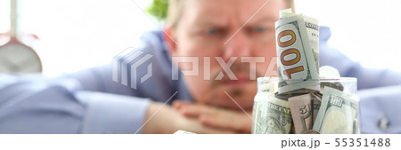 Man looking at jar full of money thinking about his debts 55351488
