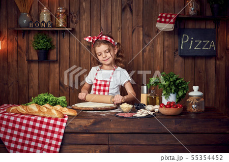 Pretty girl in checkered apron rolling out dough for pizza 55354452