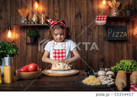 Pretty girl in checkered apron kneading bread dough for pizza Pretty girl in checkered apron kneading bread dough for pizza 55354457