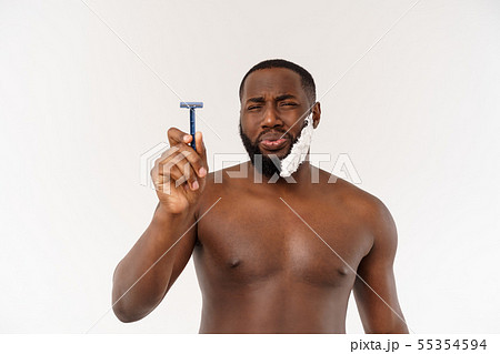 Young Afro American Man Shaving in Bathroom. Personal Morning Routine. Hygiene at Morning Concept. Young Afro American Man Shaving in Bathroom. Personal Morning Routine. Hygiene at Morning Concept. 55354594