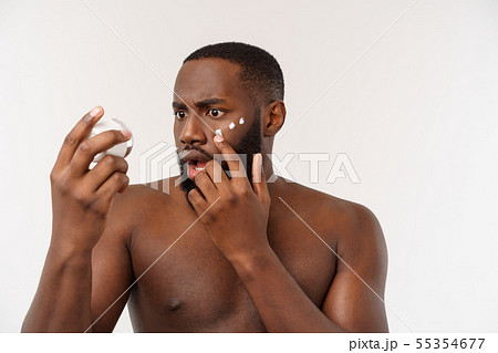 Smiling afro man applying cream on his face. Man's skin care concept Smiling afro man applying cream on his face. Man's skin care concept 55354677