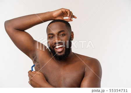 Close up of a happy naked african man shaving with razor isolated over gray background Close up of a happy naked african man shaving with razor isolated over gray background 55354731