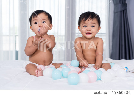 cheerful twin babies on bed 55360586