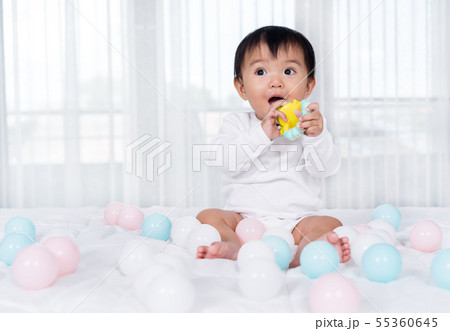 cheerful baby playing color ball on bed 55360645