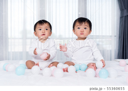 cheerful twin babies playing color ball on bed cheerful twin babies playing color ball on bed 55360655