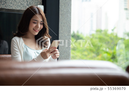 Cheerful young Asian woman using smartphone  55369070