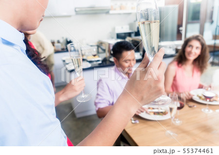 Man raising champagne flute toast with friends 55374461