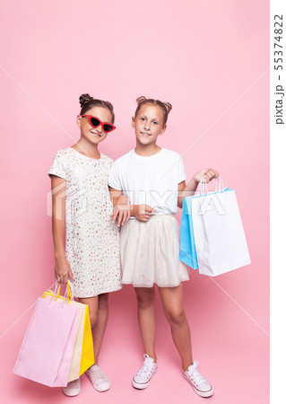 Two smiling teenage girls hold bags in their hands Two smiling teenage girls hold bags in their hands 55374822