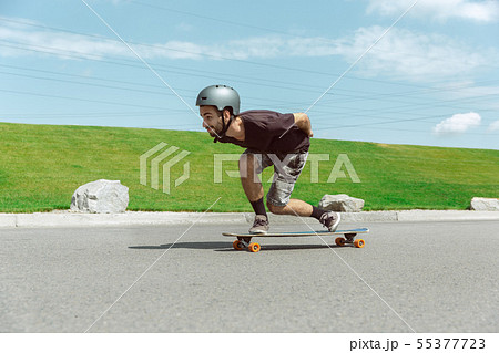 Skateboarder doing a trick at the city's street in sunny day Skateboarder doing a trick at the city's street in sunny day 55377723