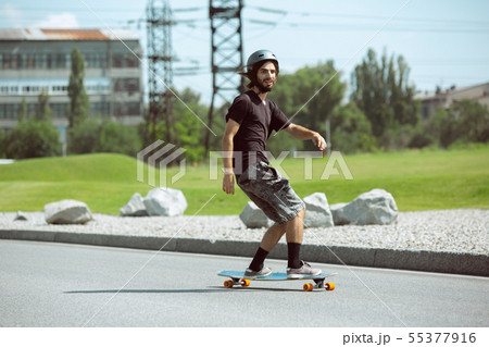 Skateboarder doing a trick at the city's street in sunny day Skateboarder doing a trick at the city's street in sunny day 55377916