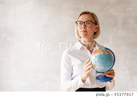 Charming teacher wearing blouse and skirt holds globe her hands Charming teacher wearing blouse and skirt holds globe her hands 55377917