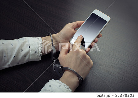 handcuffed hands with a mobile phone 55378203