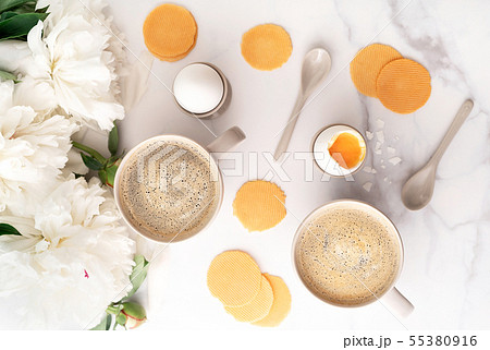 Soft-boiled eggs with liquide orange yolk in ceramic egg cups and two cups of coffee on background Soft-boiled eggs with liquide orange yolk in ceramic egg cups and two cups of coffee on background 55380916
