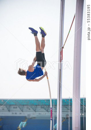 Pole vault - a young athletic man rest against the ground on the pole and ready to jump 55383195