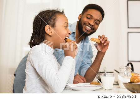 Father and daughter eating cookies, drinking milk 55384851