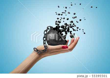 Closeup of woman's hand facing up and holding black wall and chain dissolving into pieces, on light 55395501