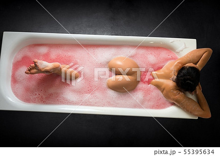 Anonymous naked woman lying in bathtub with pink water 55395634