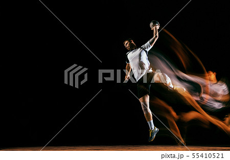 Young handball player against dark studio background in mixed light 55410521