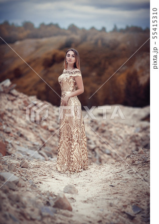 Girl in a golden dress on a background of rocks 55415310