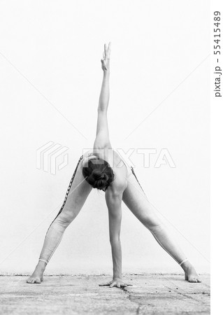 Fit sporty active girl in fashion sportswear doing yoga fitness exercise in front of gray wall 55415489