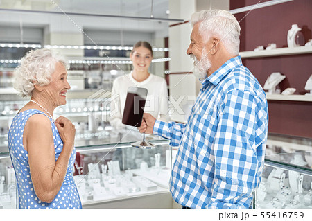 Elegant aged woman trying on pearl necklace at jewelry store Elegant aged woman trying on pearl necklace at jewelry store 55416759