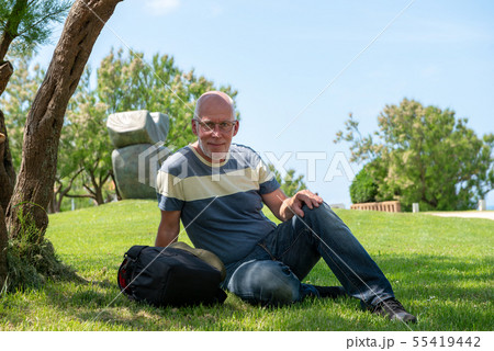 handsome mature man is resting under a tree handsome mature man is resting under a tree 55419442