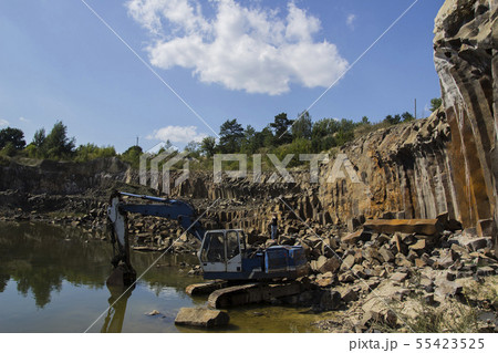 Excavator and basalt columns rocks. Heavy industry Excavator and basalt columns rocks. Heavy industry 55423525