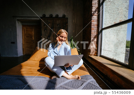 Smiling attractive woman lying on bed using laptop Smiling attractive woman lying on bed using laptop 55436009