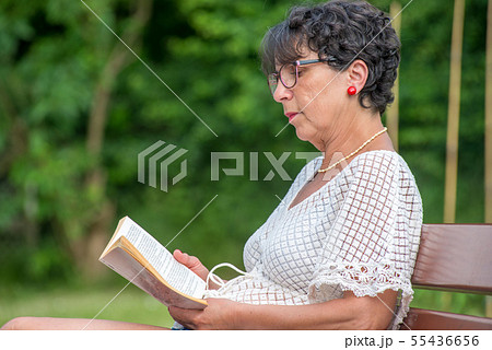 beautiful senior woman reading book in the garden 55436656