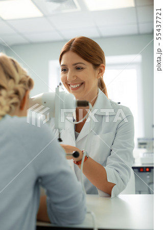 Eye doctor laughing while talking to girl during consultation 55437721