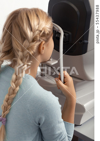 Teen girl wearing blue sweater having eye specialist consultation 55437988
