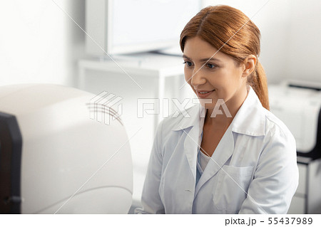Beautiful red-haired ophthalmologist feeling good while working Beautiful red-haired ophthalmologist feeling good while working 55437989