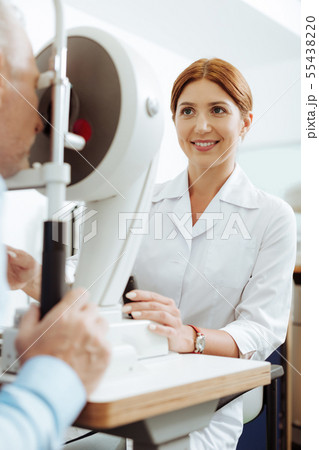 Red-haired beaming ophthalmologist feeling good while working 55438220